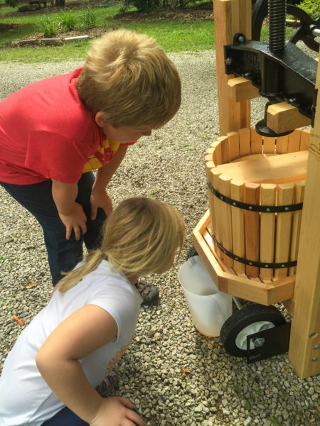 kids looking at juice coming out of the cider mill