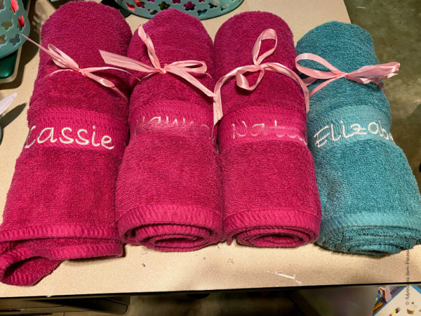 pink and teal towels tied with a bow with embroidery names on them