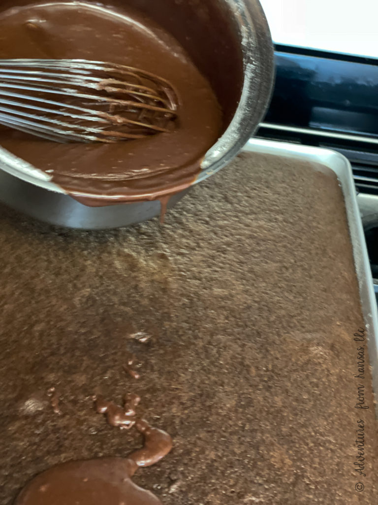 Baked Gluten Free Chocolate Sheet Cake with icing being poured on