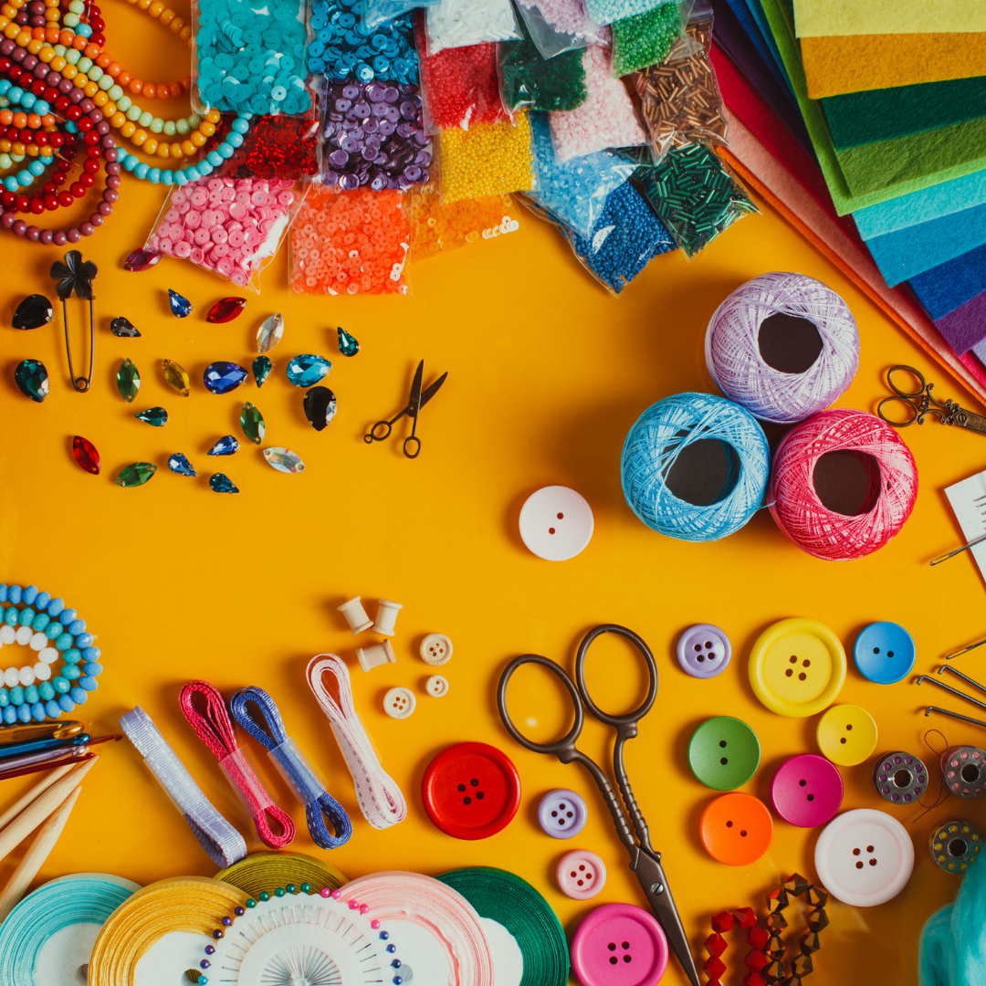 beads, yarn, jewels, scissors, and other craft items on yellow background