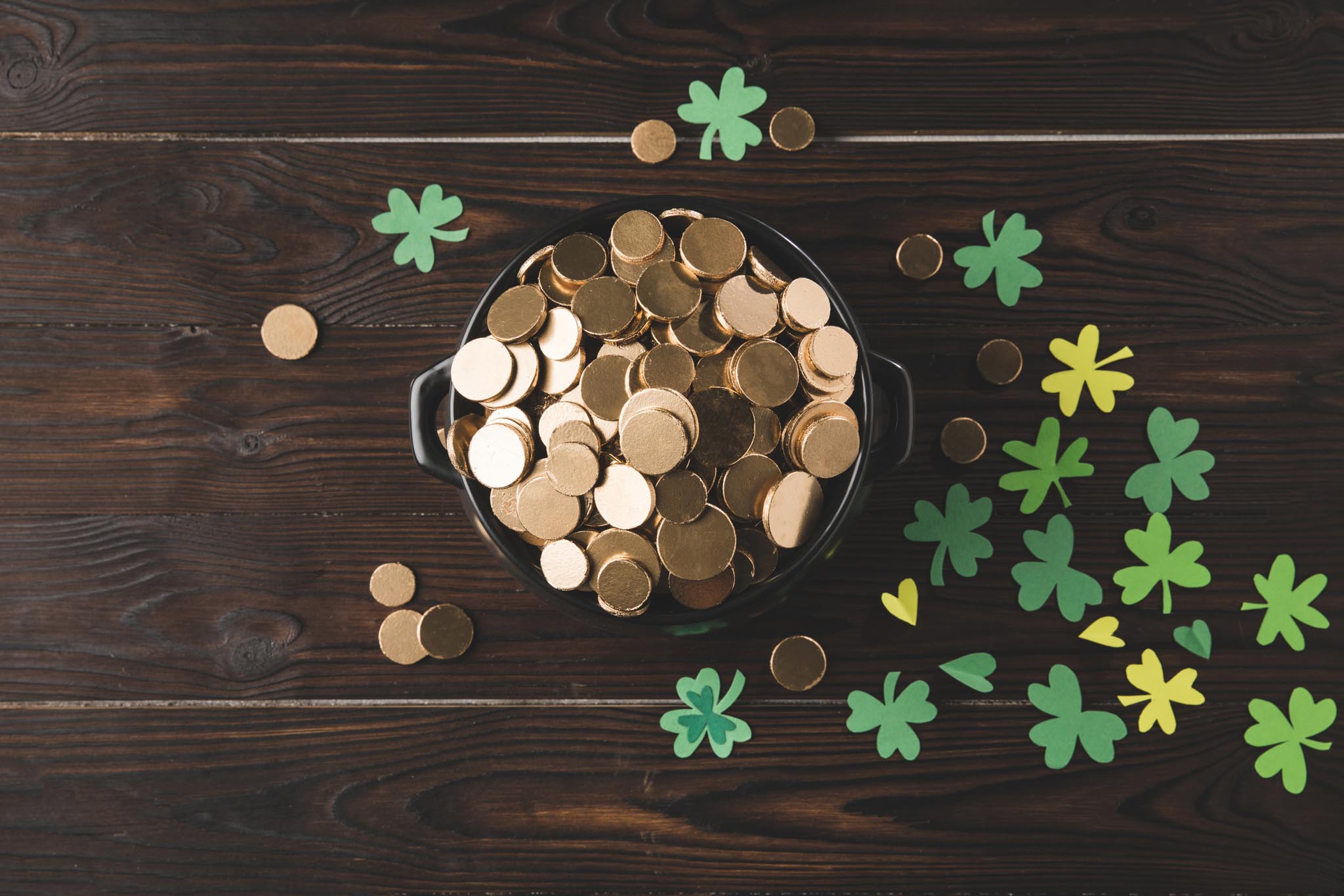 dark wood background, cut out shamrock around a pot of gold