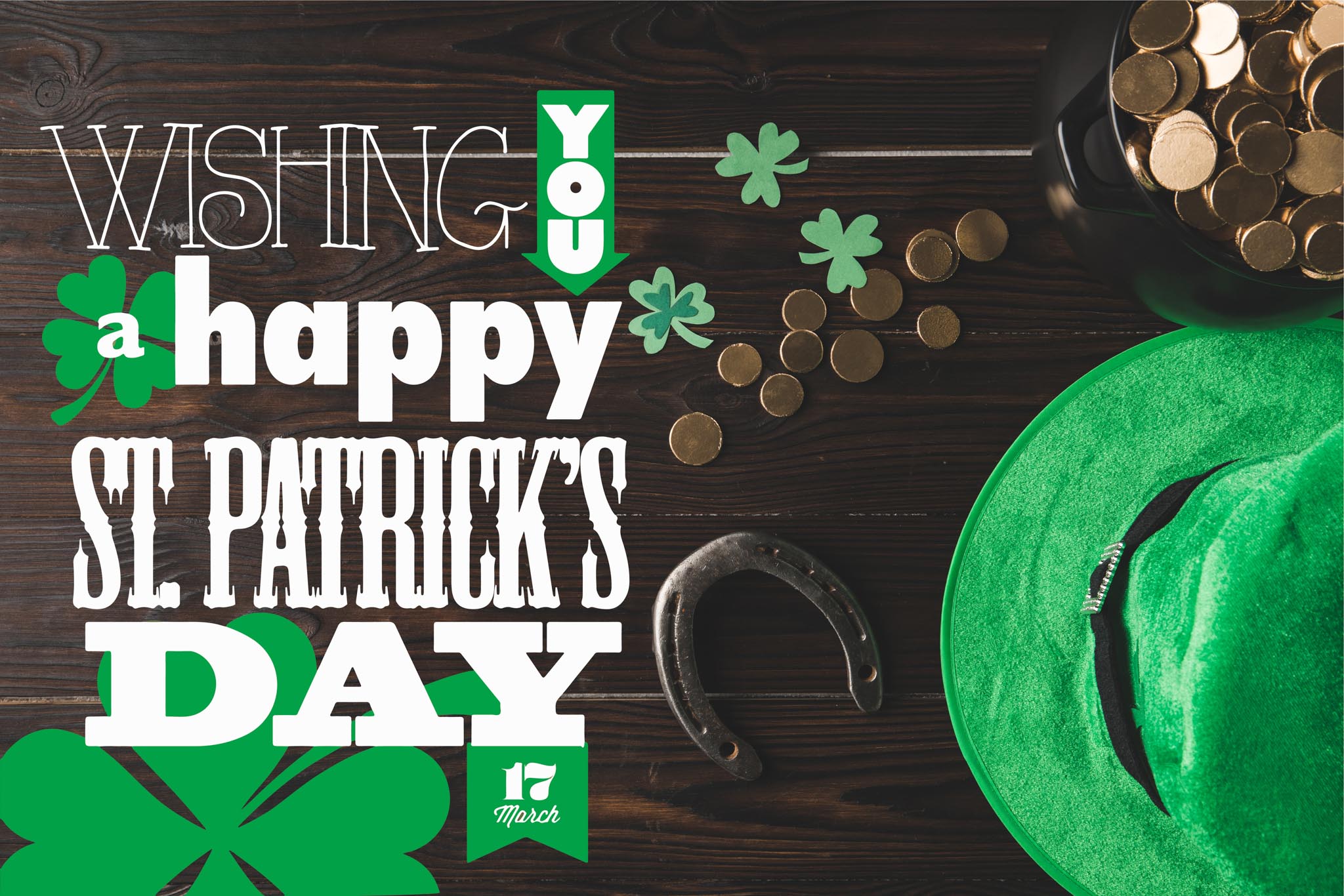 dark table with shamrocks, green hat, and gold coins and the words wishing you a happy st patricks day march 17