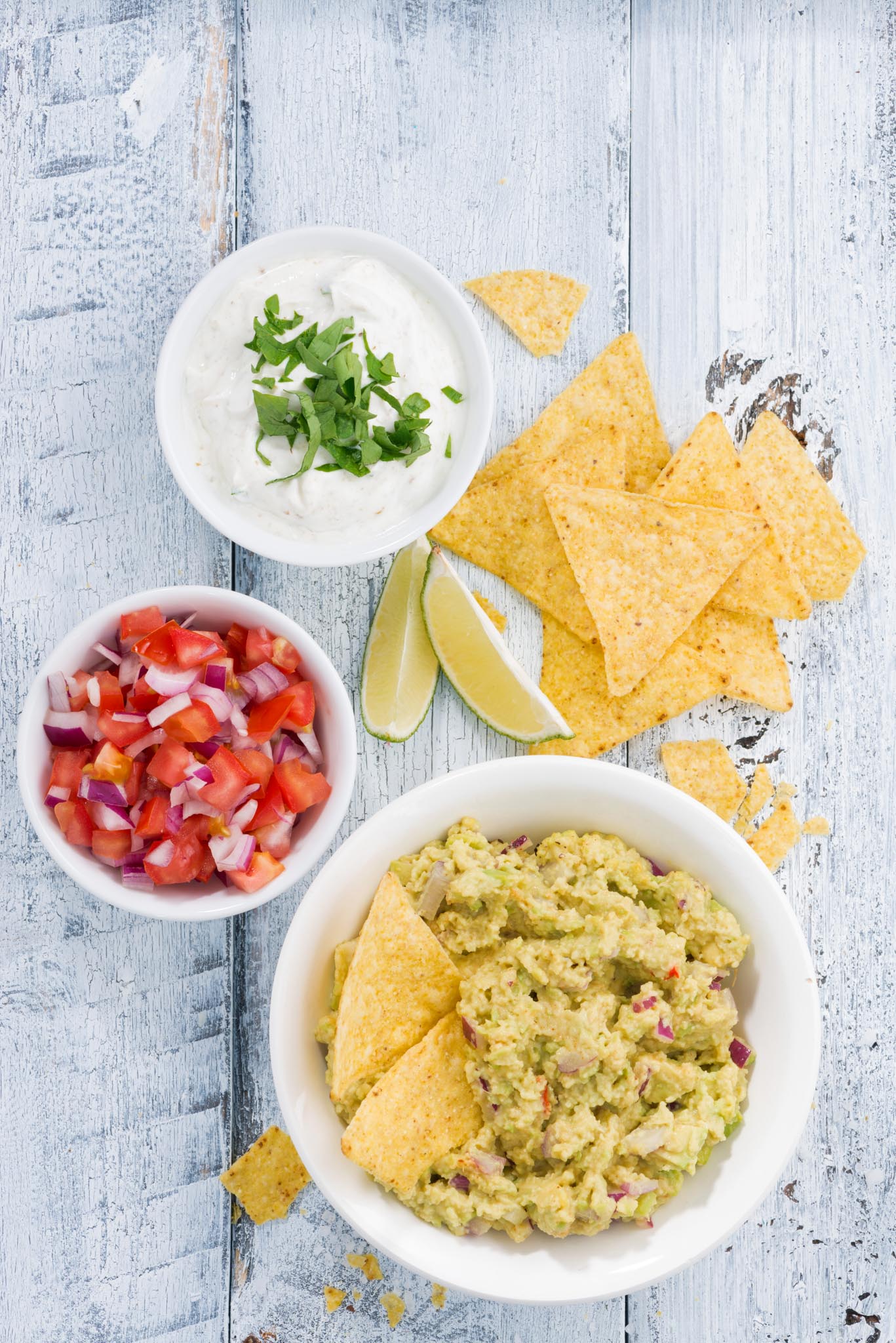 spicy avocado sauce and assorted sauces with corn chips on wooden table, vertical, top view