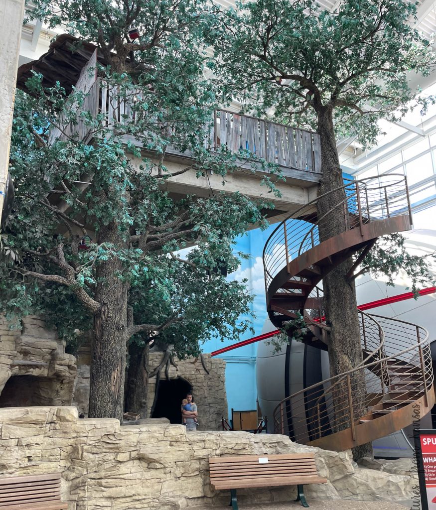 tree house with stairs and rocks with a bench